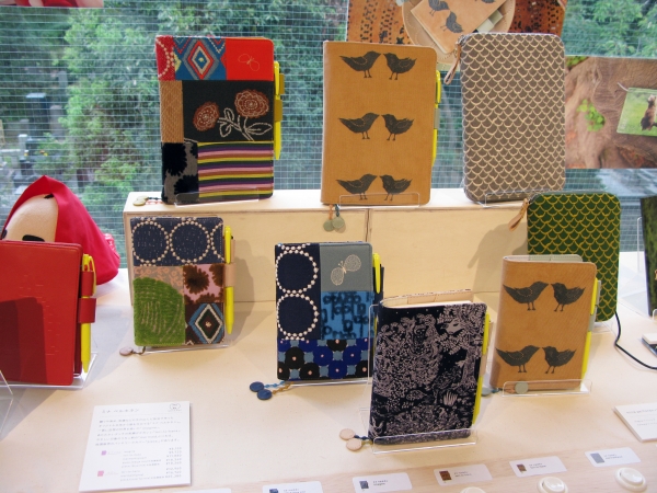 手描きの図案をもとに、織や刺繍による独自生地で服を仕立てる「ミナ ペルホネン」の手帳カバー