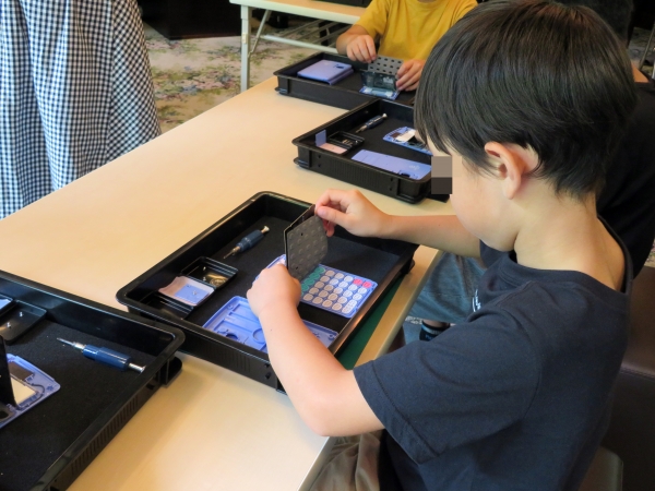 電卓の蓋を開き基盤の中身をはじめて見て驚く子どもたち