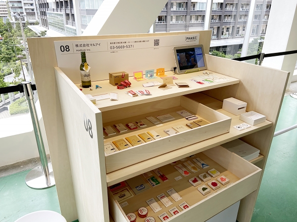 出展社は遠隔参加 来場者のみ会場をまわる形式とし オンラインではできない 製品の質感・手触りを自身の感覚で確かめることができる。